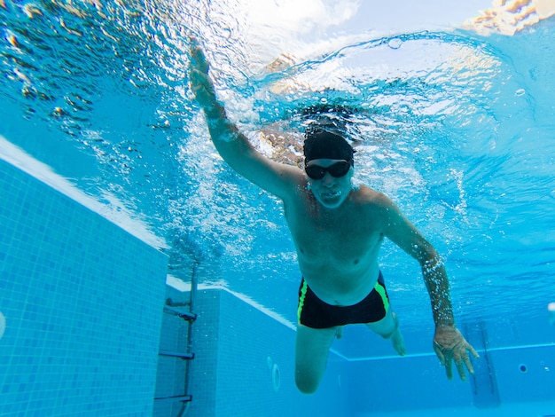 One active senior alone in the pool swimming and training to be healthy and a fitness man - summertime having fun at the swimming pool