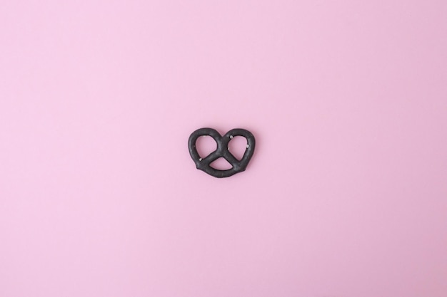 One black pretzel on a pink background full screen