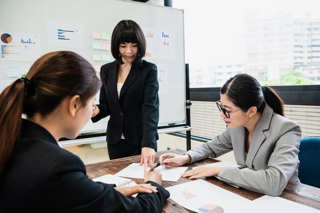 one businesswonman is introducing her project and her colleagues writing notes in the office during the morning meeting.