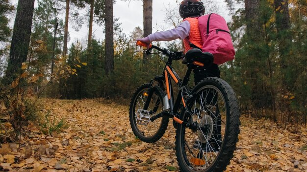 One caucasian children walk with bike in autumn park Little girl walking black orange cycle