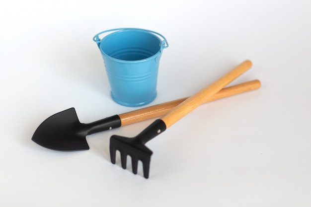 One colorful blue bucket with shovel and rake on white