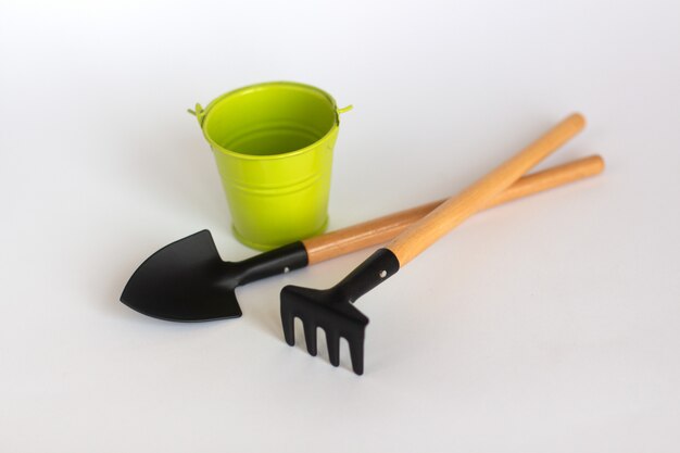 One colorful  green bucket with shovel and rake on white 