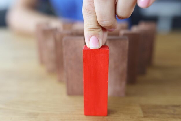 One different red cube block among wooden blocks closeup individuality leadership and