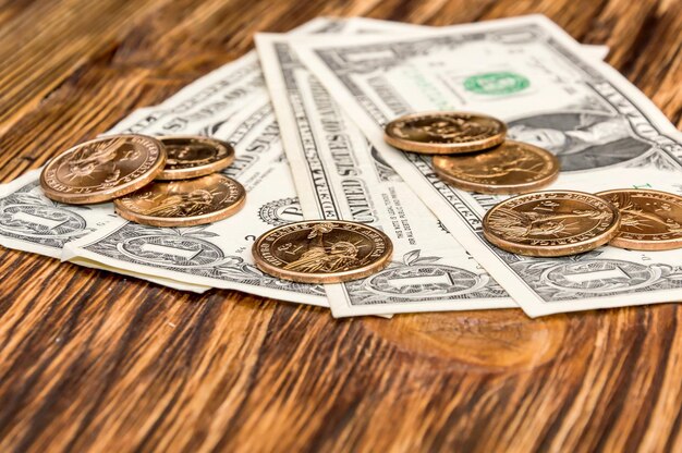 One dollar banknotes and one dollar coins on wooden background