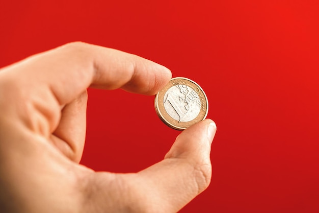 One euro coin in man hand on a red background