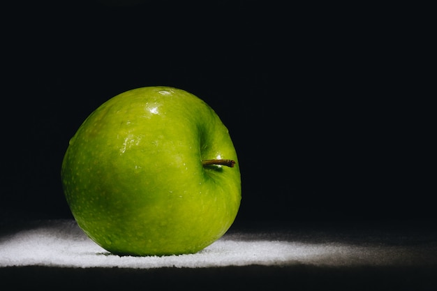 One fresh green apple on a dark background