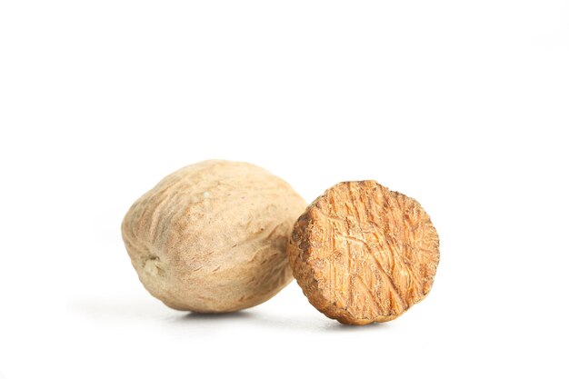 One and a half nutmegs in a close up view on a white background with copy space