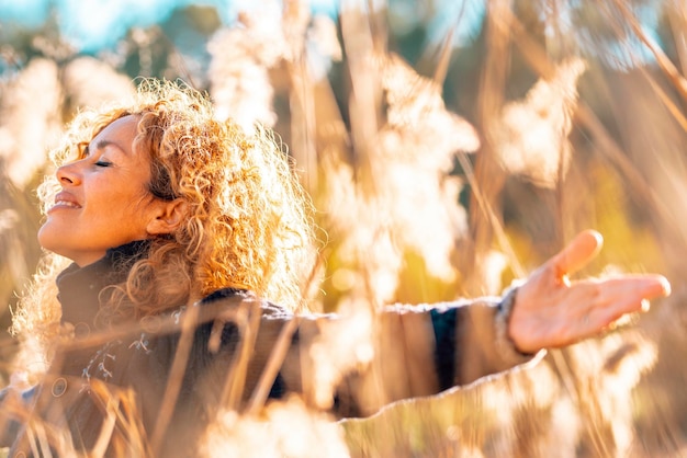 Photo one happy woman outstretching arms in a high yellow grass field in sunset golden sunlight smiling and breathing to enjoy nature and love environment and sustainability people female success lifestyle