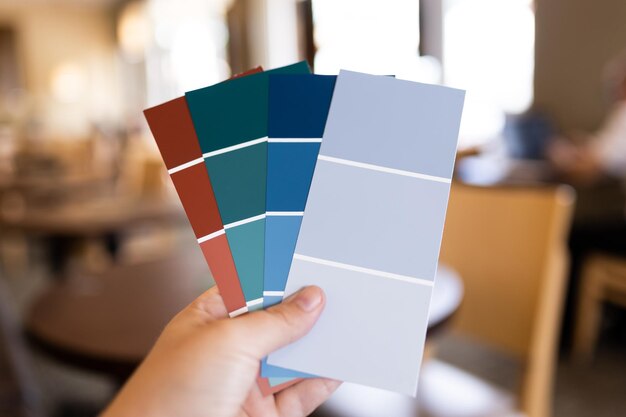 Photo one human hand holding several paint swatches interior design remodel paint sample