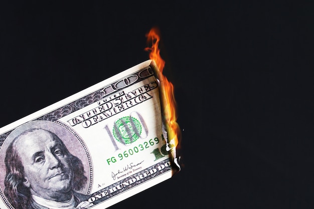 One hundred American dollar burning in fire flame. collapse of dollar. Devaluation. Falling currency