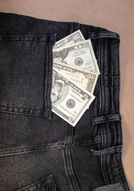 One hundred dollar bill sticking out of the pocket of black jeans