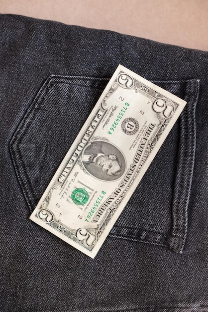 One hundred dollar bill sticking out of the pocket of black jeans