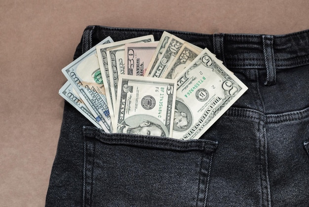 One hundred dollar bill sticking out of the pocket of black jeans