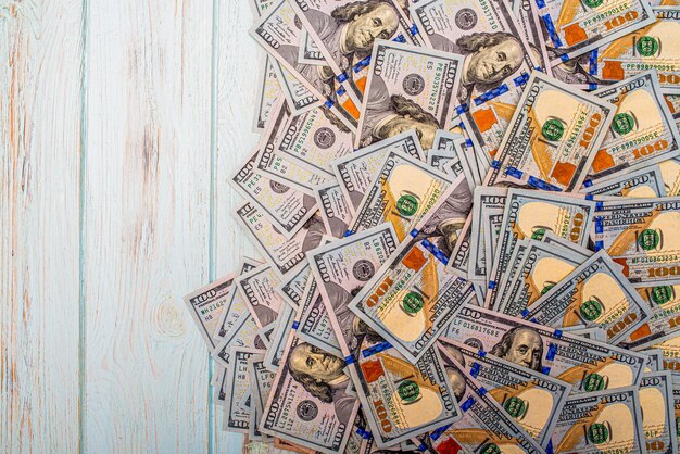 One hundred dollar bills on a blue background American currency on a wooden background