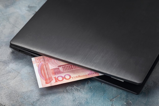 One hundred yuan sticking out of a laptop concept on the theme of remote work