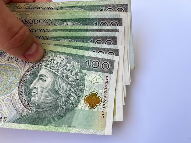 One hundred zloty bills close-up in hand on a white isolated background