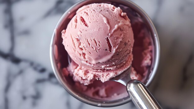 One large scoop of homemade strawberry ice cream in a metal cup with a silver spoon