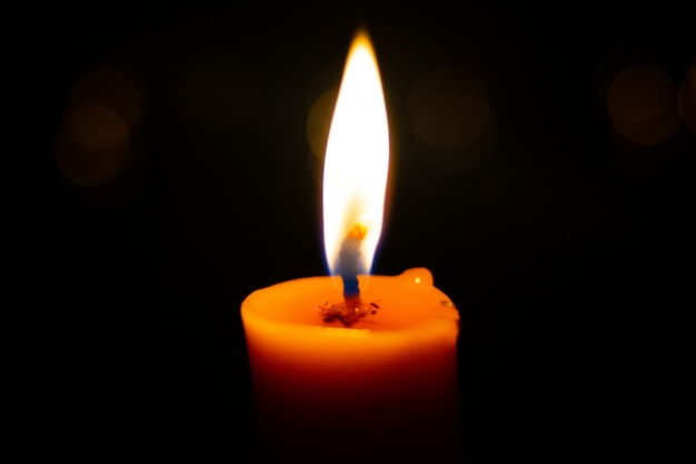 One light candle burning brightly in the black background