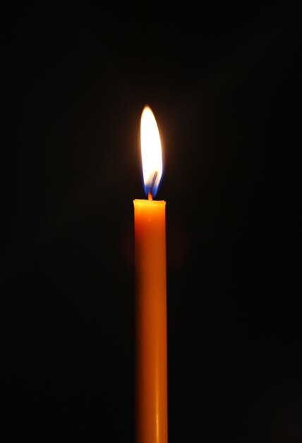 One light candle burning brightly in the black background