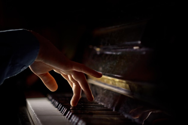 One male hand on the piano The palm lies on the keys and plays the keyboard instrument in the music school student learns to play hands pianist black dark background