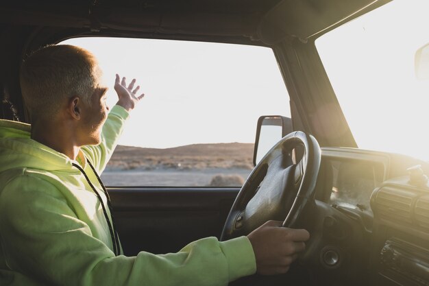 One man driving his car looking and enjoying the beautiful landscape sunset -  young teenager driving a car - having fun in his vacations travelling in a tour