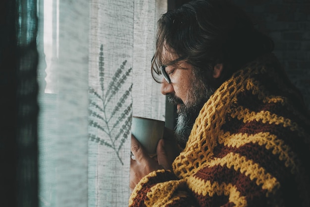 One man suffering cold temperature condition inside home for gas energy saving and price bills Side view of male people drinking coffee or tea Influenza flu cold symptoms and bad health condition