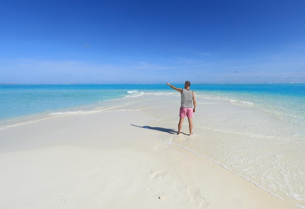 one man on a tropical island with white sand in the ocean