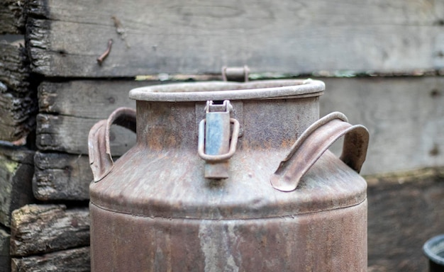 One old rusty metal can in the countryside Container for transporting liquids milk or liquid fuels with multiple handles Milk bank of a cylindrical form with a wide mouth Bottle with sealed cap