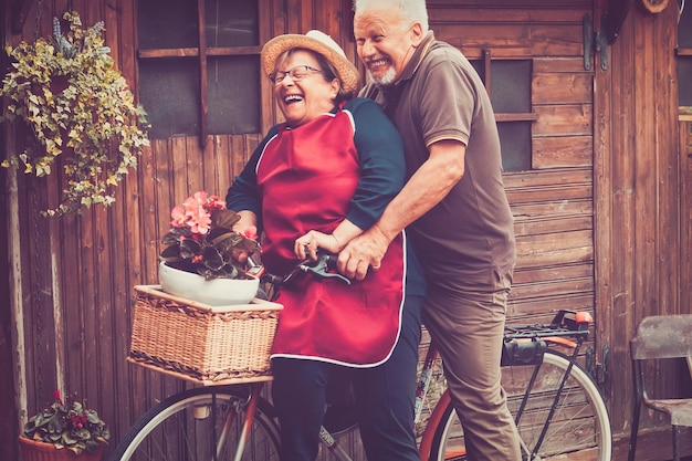 One old senior couple have fun together playing and joking outdoor on a bike Active mature man and woman aging youthfully with love and happiness Active lifestyle for elderly people enjoying life