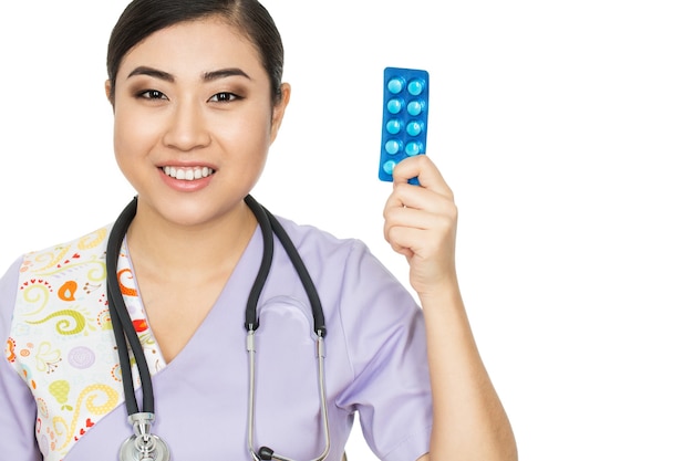 One per day. Studio shot of a female doctor holding medication smiling cheerfully isolated on white