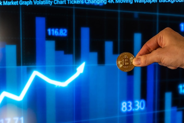 One person showing his fingers holding a cryptocurrency bitcoin with stock market charts in the background