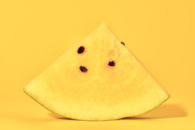 One piece of yellow watermelon with seeds on yellow background delicious refreshing fruit