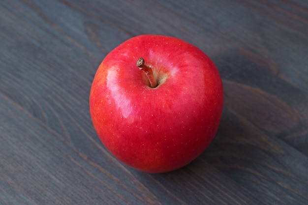 One red apple isolated on dark colored wooden table