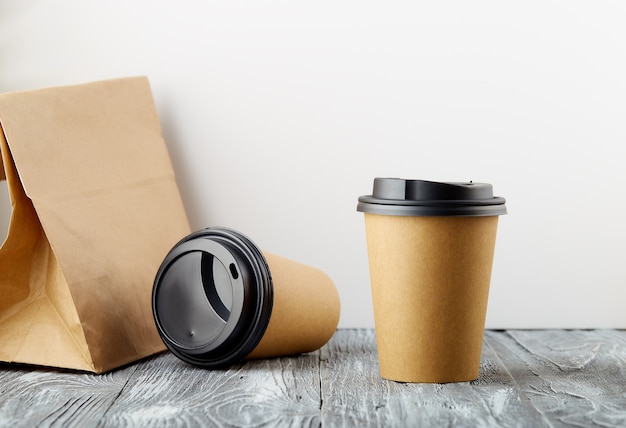 One rest and one cost take away paper coffee cups with lunch bag on wooden background