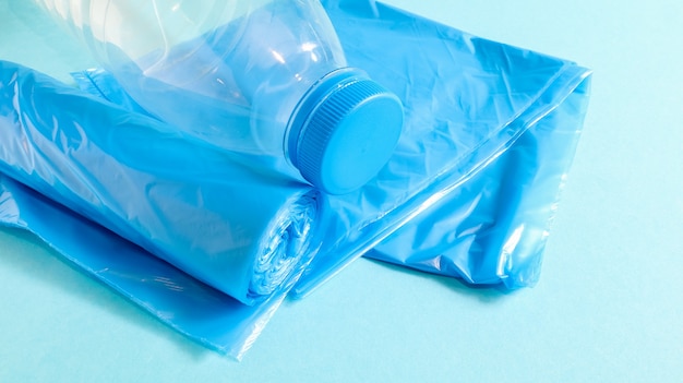 One roll of plastic trash bags in blue on a blue background. Bags that are designed to accommodate garbage in them and used at home and placed in various garbage containers. Copy space.