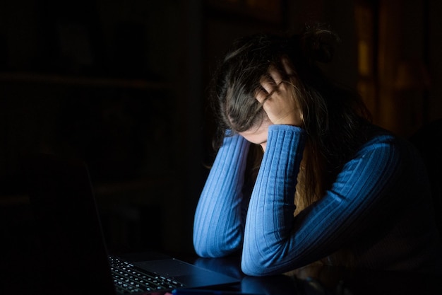 One sad and tired young woman feeling bad covering her face with hands while working at home indoor Female girl exhausted and stressed studying at nightxA