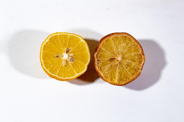 one slice of fresh and rotten lemon served on a plain white background