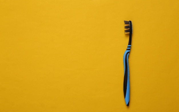 One toothbrush on yellow background Top view Dental care concept Copy space