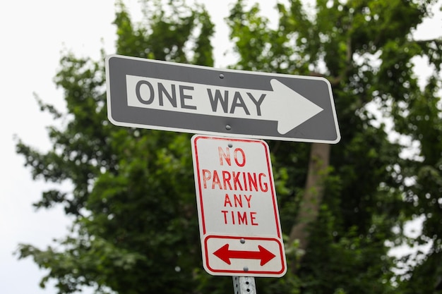 A one way street sign that says no parking any time.