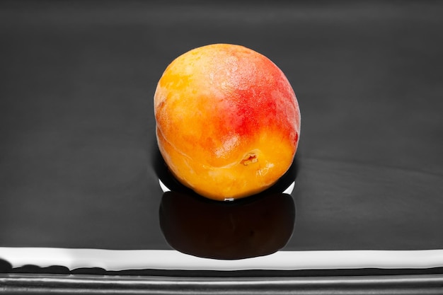 One wet apricot in water on a dark background Fresh juicy ruddy apricot in a dark clay plate