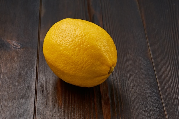 Photo one whole bright yellow ripe delicious organic lemon on a natural wood