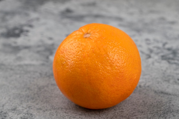 One whole fresh healthy oranges isolated on a stone table.