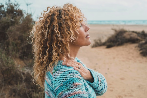 One woman enjoy inner balance and meditation leisure outdoor activity alone feeling nature hugging herself at the beach Side portrait of zen lifestyle and happiness female people Closed eyes love