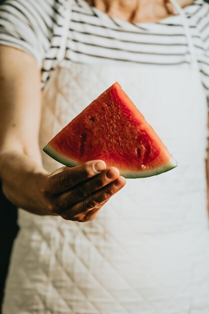 One woman holding a slice of watermelon to camera, healthy food and eating wellness concepts