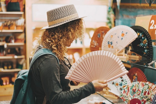 One woman in shopping leisure activity inside a store touching folding fans for heat temperature and climate change earth condition Concept of female people in shop activity for gifts or pleasure