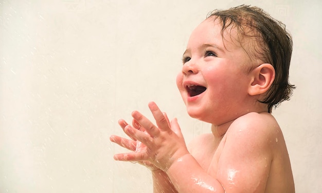 One year old baby girl laughing and playing in the bath