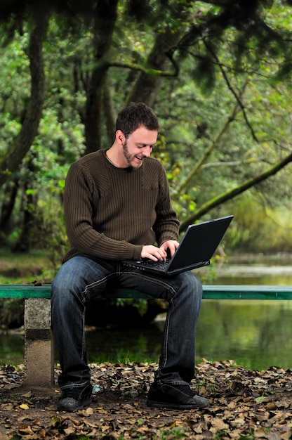 one young businessman working on laptop outdoor with green nature in background