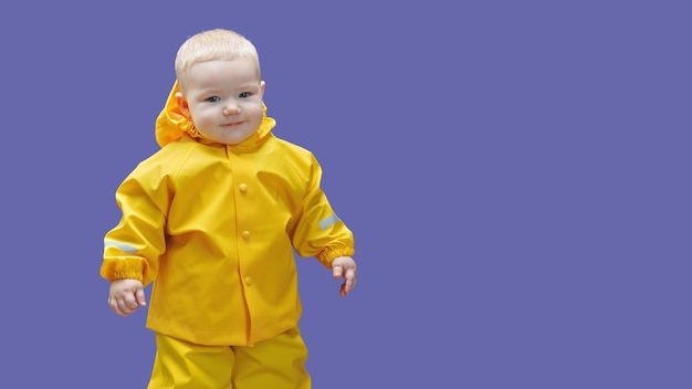 Oneyearold baby in yellow waterproof suit on purple background