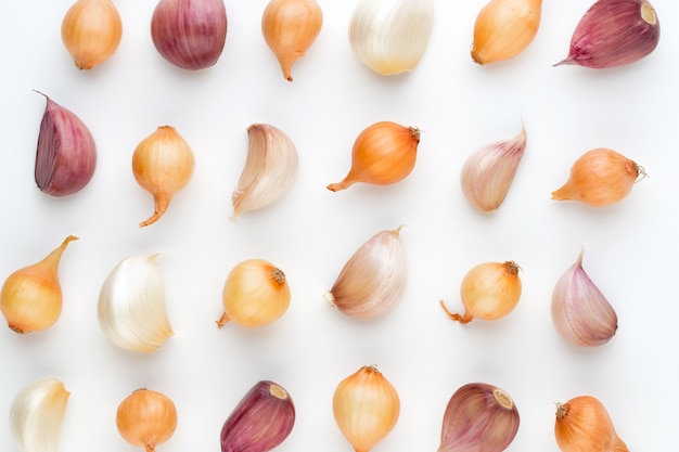 Onion and garlic isolated on white background, top view. Wallpaper abstract composition of vegetables.