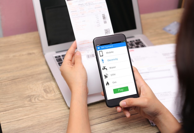 Online bill payment concept.Hands holding mobile phone on blurred Electric bill as background